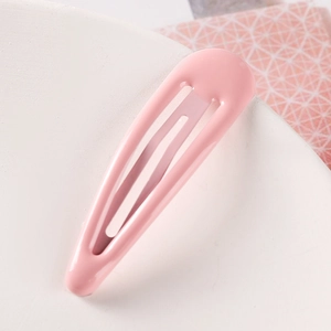 Detail view of a glossy bright pink metal drop hair clip on a minimalist background