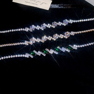 Detailed close-up of purple, champagne, and emerald zircon tennis bracelets on black velvet