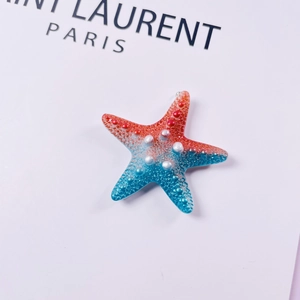 Macro detail of gradient red and blue starfish charm with pearl-like texture