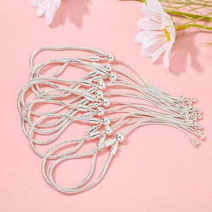 Detail of silver snake bone bracelets with round clasps and extension chains on pink background