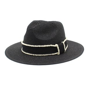 Detail of black fedora straw hat featuring white beaded wavy trim on the ribbon