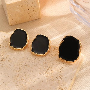 Detail of vintage irregular gold earrings with black enamel glaze and hammered texture