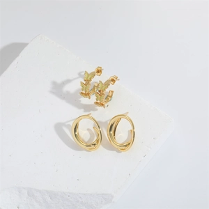 Minimalist gold butterfly earrings and double oval hoops set on white textured stones
