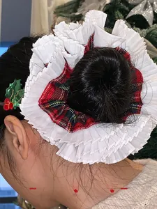 Detail of Christmas style white pleated scrunchie and holly leaf clip worn on a bun