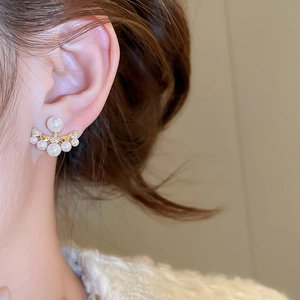 Detail of fan-shaped pearl earring with zircons worn on ear for elegant style