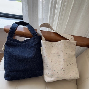 Minimalist denim and canvas tote bags in navy blue and beige on a wooden chair