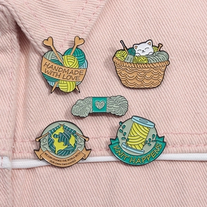 Detail showing five colorful enamel pins with knitting themes pinned to a pink denim jacket