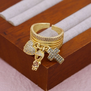 Macro detail of 18K gold ring with heart, cross, and purple figure charms and pavé diamonds
