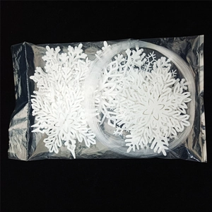 Detailed view of white hollow snowflake ornaments set with hanging string on black background