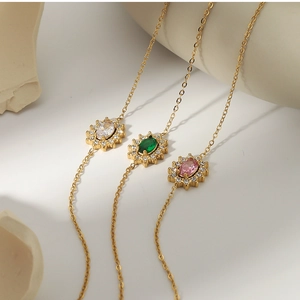 Detail of vintage gold necklaces with oval emerald, pink, and clear zircon pendants