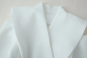 Close-up of minimalist white long-sleeve blazer neckline and shoulder stitching detail