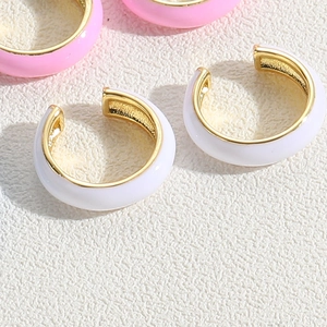 Macro shot of colorful C-shaped enamel ear cuffs in cream white and soft pink finish
