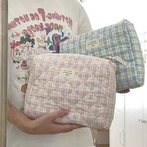 Quilted lattice makeup bag in pink and blue cotton fabric held by model hand