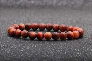 Macro shot of 8-10mm red tiger eye stone beads on a stretch bracelet with cat-eye effect