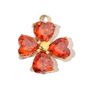 Detailed view of a four-leaf clover pendant with orange heart-shaped zircon stones