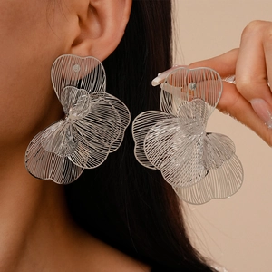 Macro shot of silver hollow floral earrings showcasing intricate metallic petal textures