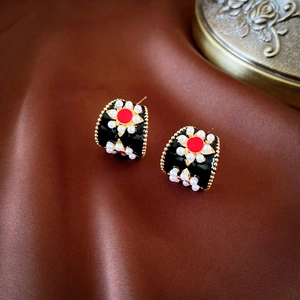 Détail de boucles d'oreilles perles vintage en C avec émail rouge sur soie marron
