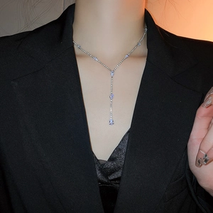 Detail of silver Y-shaped tassel necklace with sparkling crystals on a model outfit