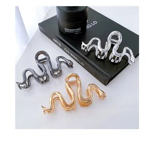 Macro detail of snake-shaped metal hair claws in gold, silver and gun black finishes