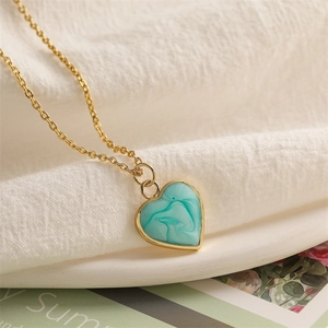 Macro detail of heart pendant with turquoise marble inlay and gold metal edging