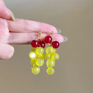 Gros plan sur les boucles d'oreilles en forme de raisin avec perles rouges et vertes