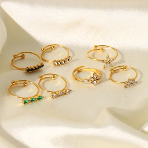 Detailed view of seven 18K gold plated open rings with green and white cubic zirconia