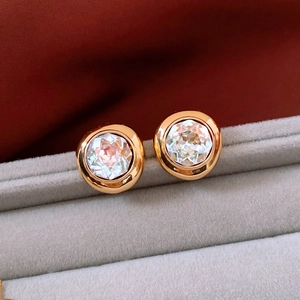 Close-up of vintage oval gold plated stud earrings with transparent crystal on velvet