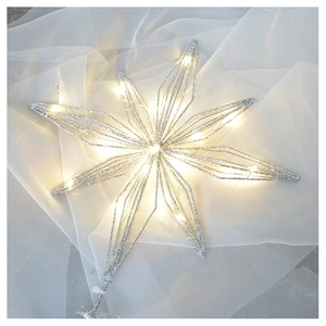 Silver glittery star Christmas tree topper with warm white LED lights on white fabric