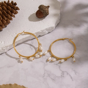 Elegant gold hoop earrings with natural baroque freshwater pearls on marble background