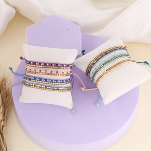 Detailed close-up of Bohemian handmade woven bead bracelet on display pillow