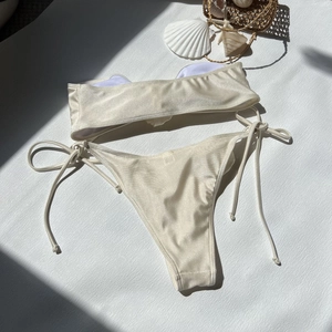 Flat lay of champagne metallic bandeau bikini with shells and starfish beach decor