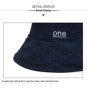 Détail d'un chapeau de soleil bleu foncé avec texture carrée et broderie blanche