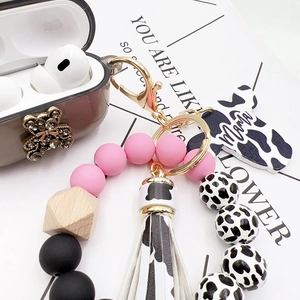 Cow print silicone earphone case with beaded wristlet, leather tassel, and Mama charm
