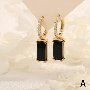 Macro shot of 18K gold hoop earrings with small diamonds and rectangular black stones