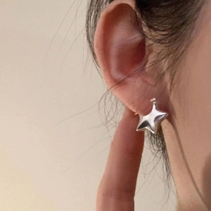 Minimalist silver star-shaped hoop earrings for women with polished finish on ear