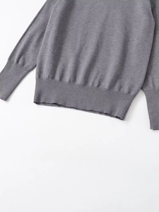 Detail of ribbed cuffs and hem on a gray knit sweater with fine textured fabric