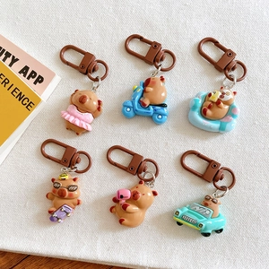 Set of six cute Capybara keychains in various poses on a white textured background