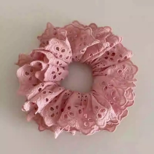 Gros plan du chouchou en dentelle rose à double couche avec broderie florale ajourée