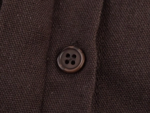 Macro shot of dark brown knit fabric texture and a round four-hole resin button detail