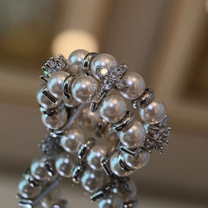 Macro shot of double-layered pearl ring with zircon floral detail and mirror reflection