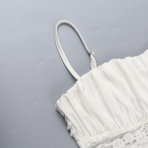 Close-up of white lace camisole top with ruffled chest design and delicate hemline details