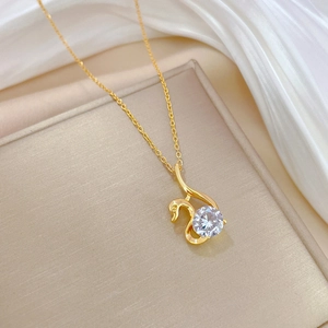 Elegant gold swan pendant necklace with a sparkling round zircon on white silk background