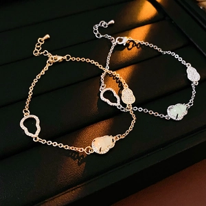 Close-up of gold and silver hollow gourd bracelets with zircon and green jade on black tray