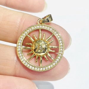 Close-up of golden sun pendant with white zircon inlay and carved face detail