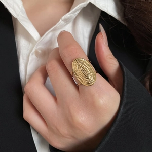 Detail of a textured gold oval embossed metal ring worn on a model's index finger