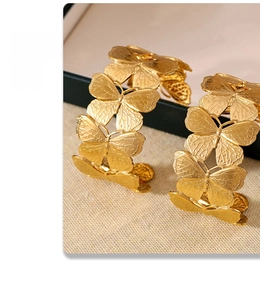 Detailed close-up of 18k gold plated butterfly cuffs with intricate metallic textures