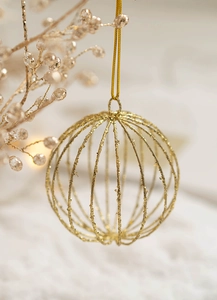 Detail of golden hollow glitter Christmas ball ornament hanging with festive bead strings