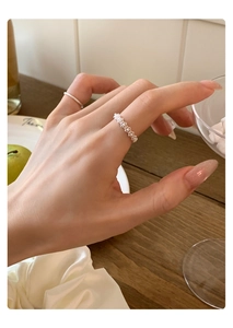 Detailed view of silver lace-textured ring with delicate woven beads on female hand