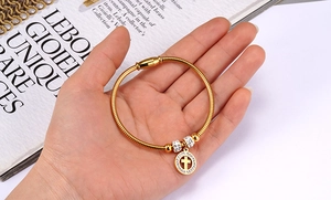 Detail of a gold-plated bracelet with cross pendant and sparkling zircon stones on a model