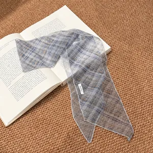 Vintage blue plaid chiffon skinny scarf accessory for women displayed on a book